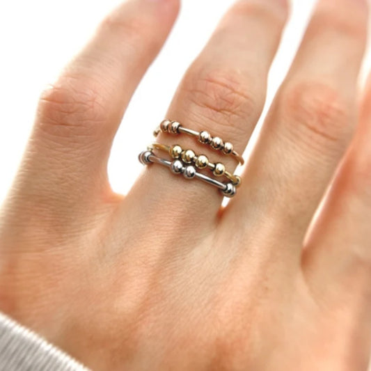 Three stacked fidget bead rings in rose, gold and silver on a hand